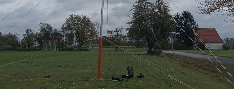 Windmessmast einer Windreaktionsmessung vor noch belaubten Laubbäumen im Oktober